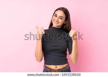 Young girl over isolated pink background with thumbs up gesture and smiling