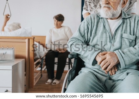 Senior man after stroke sits in a wheelchair at a nursing home