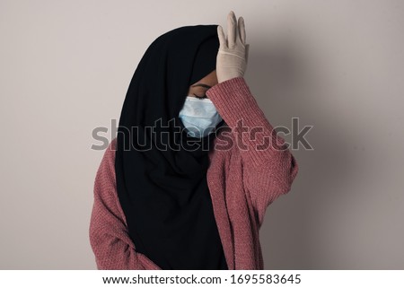 Frustrated Muslim woman wearing casual clothes holding hand on forehead being depressed regretting what she done having headache. Confused female with frowned face looking stressful having some pain