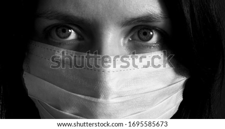 Black and white photo of a sad girl in a white medical mask. Epidemic, pandemic, coronavirus, Covid-2019. Royalty-Free Stock Photo #1695585673