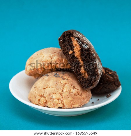 Close-up of brown cookies on a white saucer on a blue background. square photo
