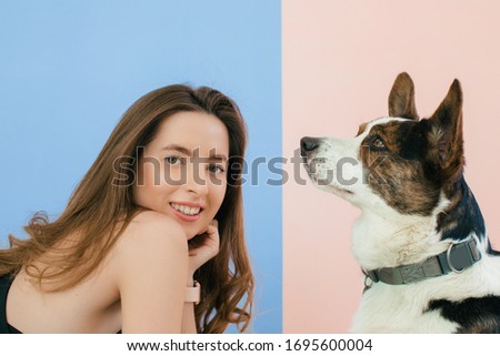 Wonderful european female model chilling in studio with dog. Indoor portrait of debonair girl enjoying photoshoot with her cute pet.