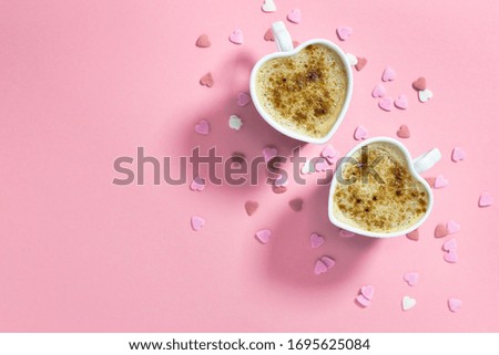 Two heart-shaped coffee cups on pastel pink background, top view with copy space. Concept of love.