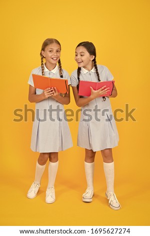 School library. Educational books for schools. Reading books. Homeschooling concept. Literacy club. Cute children holding books on yellow background. Little girls with encyclopedia or childrens books.