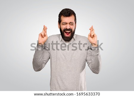Handsome man with fingers crossing over isolated grey background