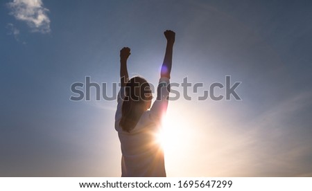 Woman with fist in the up to the sunset sky, people winning, power, determination and strength concept.  Royalty-Free Stock Photo #1695647299