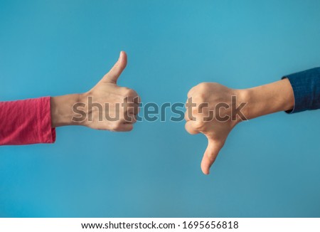 Two people making hand sign thumbs up and thumbs down, yes or no, like or dislike concept.  Royalty-Free Stock Photo #1695656818