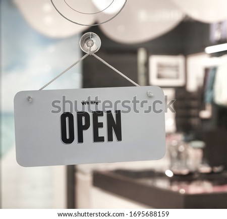 white plastic  sign board hanging on door of clothing store
