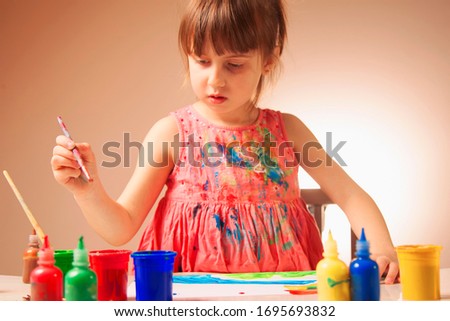 Beautiful little child girl artist with brush painting picture. Art, creativity and people concept. Selective focus on brush.