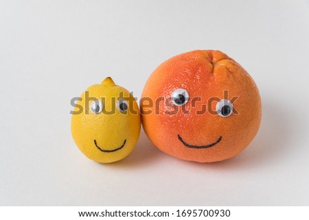 Lemon and orange with funny smiley face on white background. concept is different from others
