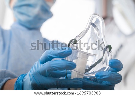 doctor in protective equipment and gloves put on oxygen mask patient diagnosis of coronavirus and Pneumonia   Royalty-Free Stock Photo #1695703903