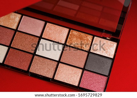 Makeup eyeshadow palette on the red background. Close up.