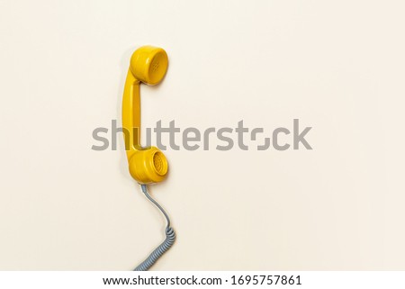 Old fashioned handset on beige color background. Modern retro style. New old technology. Copy space. Concept of Color of the Year 2021 with bright illuminating yellow and gray colours.