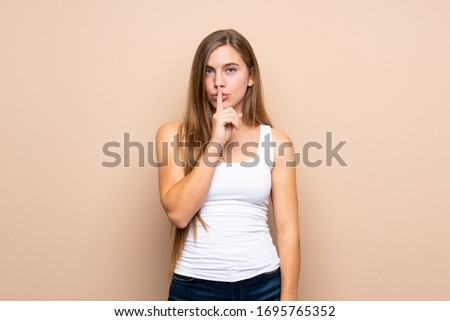 Teenager blonde girl over isolated background showing a sign of silence gesture putting finger in mouth