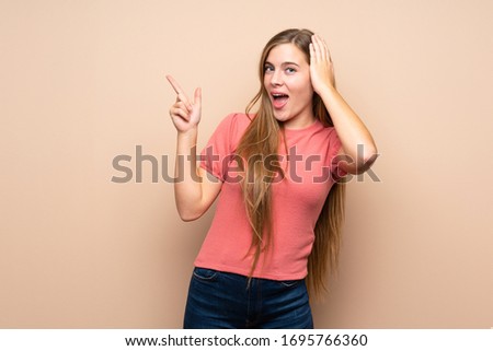 Teenager blonde girl over isolated background surprised and pointing finger to the side