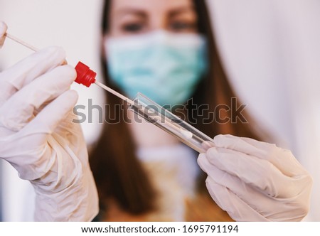 Close up of young woman with sample swab. Selective focus on sample. Corona virus protective measures.