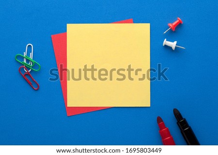 Yellow note with empty place for your text with marker and various stationery on blue background. 