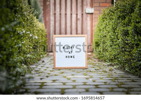 'Stay at home' words on a wooden lightbox, standing in the entrance
 to the house door, Safety concept.
