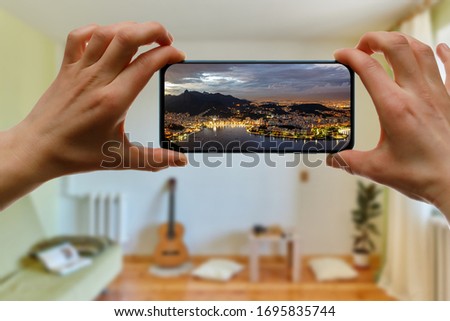 Concept of travel on a smartphone. Stay at home tourism. Online travel to Rio De Janeiro. View from sugarloaf on a screen.