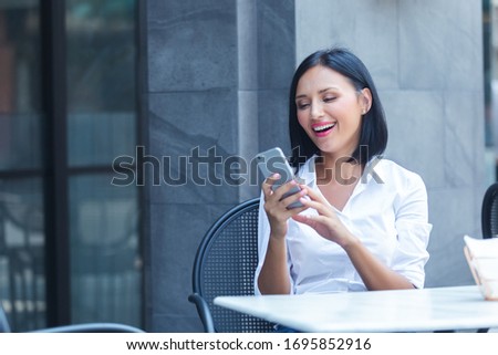 Happy woman using smartphone work online in cafe.