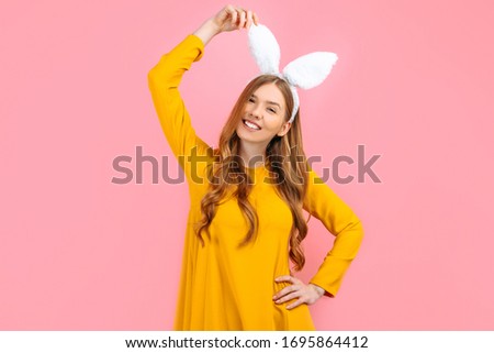 Holiday season of rabbit and eggs. Happy stylish woman in Easter Bunny ears isolated on pink background.