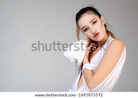 Beautiful young woman, fashion and the image of the luxury make-up. Fashion photo of a beautiful young woman in a pretty dress over gray background. Fashion photo Royalty-Free Stock Photo #1695875572