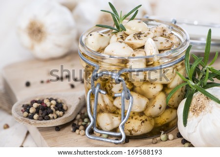 Garlic (preserved) in a glass on wooden background