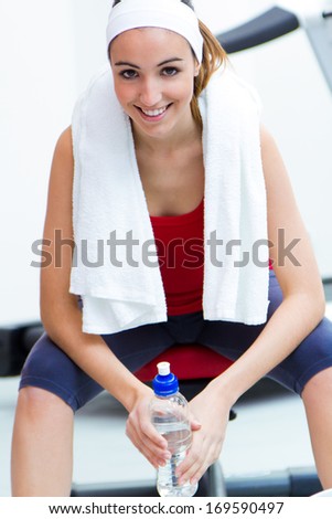 Happy young woman relaxing in the gym after making exercise