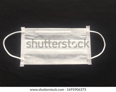 Surgical mask for personal protection isolated on a black background. Typical three-layer surgical mask for covering the mouth and nose. The procedure with a bacterial mask. Protection concept. Place