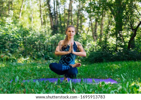 Young caucasian woman doing yoga exercises in summer city park.