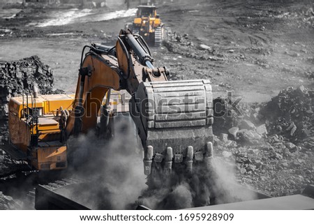 Excavator work loading of coal into Yellow mining truck. Open pit mine industry. Royalty-Free Stock Photo #1695928909