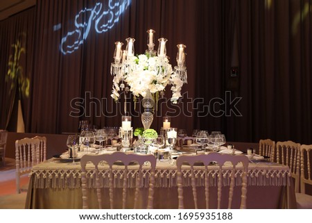 The white and cream wedding table is decorated for a decorative and elegant wedding. The wedding table has flowers, candles, glass and a plate. 