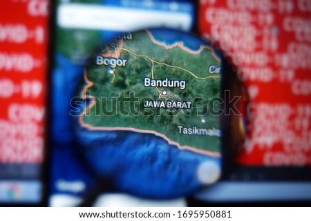 Bandung, West Java/Indonesia on google maps under magnifying glass with Red Covid-19 text Background.                               Royalty-Free Stock Photo #1695950881