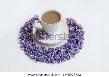 
A cup of hot morning coffee and lilac flowers on a white background. View from above. Close-up. Copy space for text. The concept of holidays and good morning wishes.