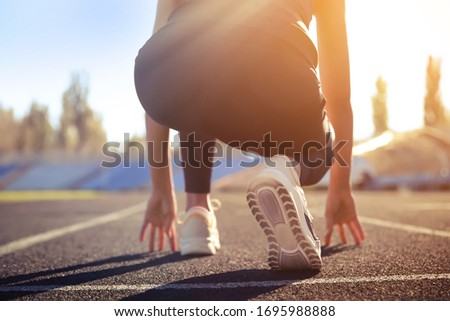 Sporty woman ready for running at stadium on sunny morning, closeup