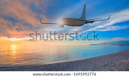 Airplane taking off from the airport - passenger airplane flying above tropical sea at amazing sunset