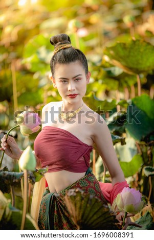 Asian woman collecting lotus flowers and she wear Traditional Thai dresses, Thailand