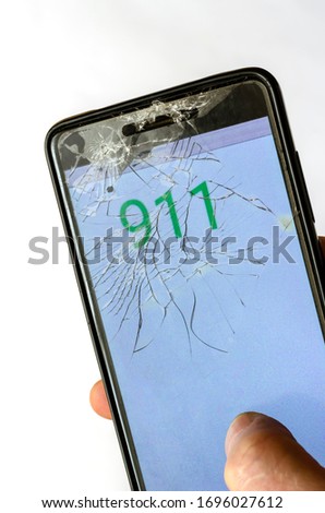 Broken Phone In A Hand. Hand holding cellphone with emergency number 911. Emergency and urgency, dialing 911 on smartphone screen. Top view at an angle. Selective focus.