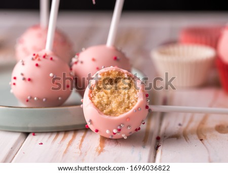 The pastry chef decorates cake pops with satin ribbons. Desserts with pink cream. Tasty food Royalty-Free Stock Photo #1696036822