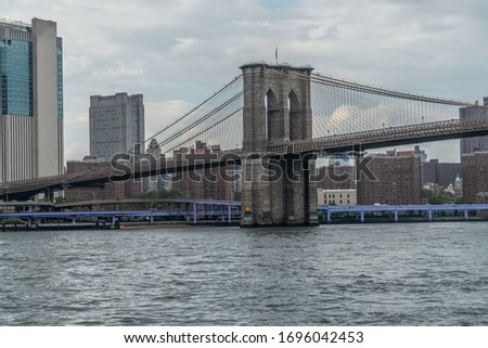 Cloudy Sky Over The Brooklyn Bridge With Urban Neighborhood In Background.