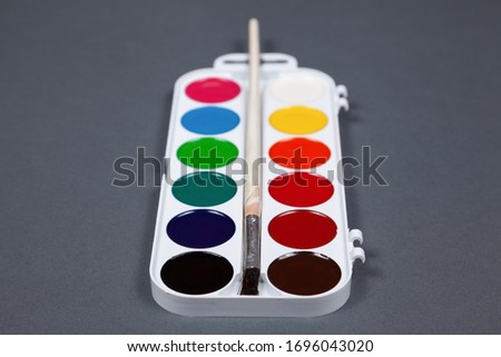 Palette of watercolor paints on a gray background