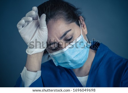 COVID-19. Exhausted Doctor looking worried as the coronavirus infected cases and death tolls rises. Emotional stressed of health workers needing support, Personal Protective gear and medical supplies. Royalty-Free Stock Photo #1696049698