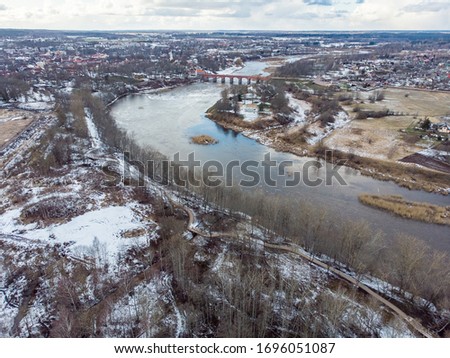 Areal drone photography view of small countryside city Kuldiga, with river Venta. Photo taken in warm winter day with snow.