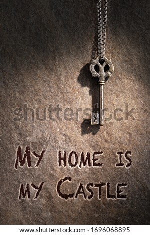 vintage vintage key on a chain on a wall background, the inscription on the wall "my house is my castle"