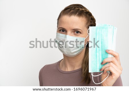 Woman in a protective medical mask holds in her hands a protective medical masks on a white background.
