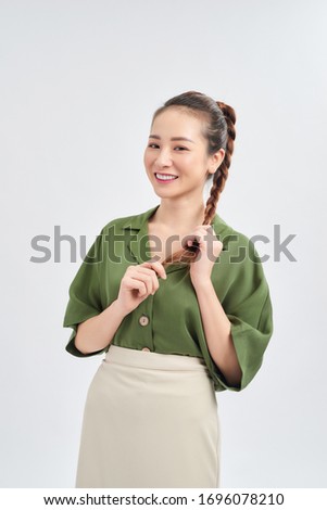 Elegant young Asian woman holding her long hair and standing isolated over white background.