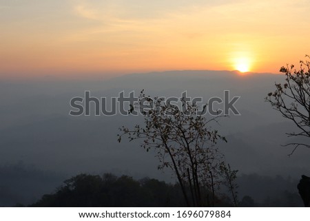 The rising sun from the back of the mountain. The golden light sparks all over the sky. Beautiful natural scenery pictures.