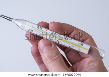 A hand holding thermometer showing high body temperature