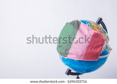 Globe in a medical mask with the flag of Italy. World pandemic concept.