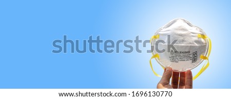 Hand holding N95 mask for protection against pollution, virus, flu and coronavirus (Covid-19). Protection pm 2.5. Air face mask. Medical mask. isolate on blue background with clipping path. Copy space Royalty-Free Stock Photo #1696130770